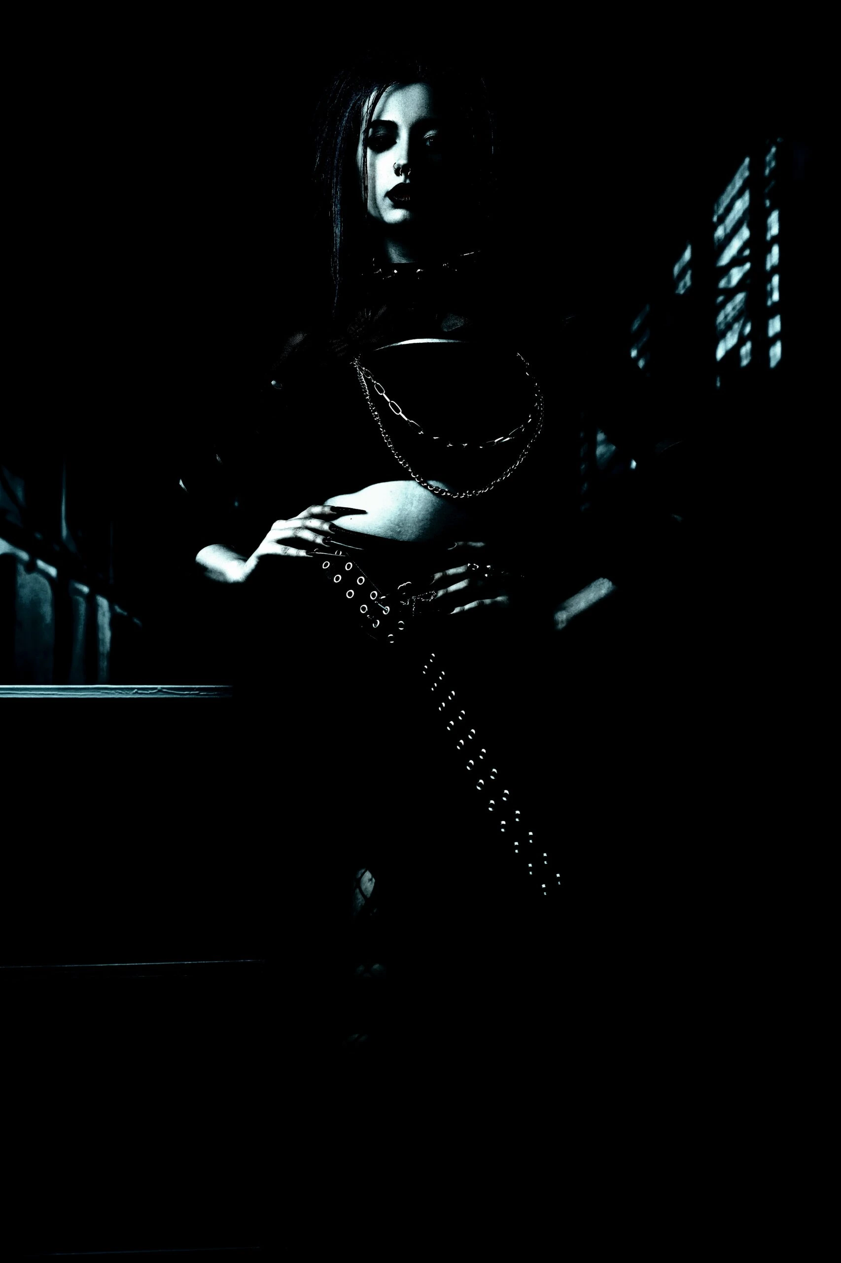 Woman wearing sunglasses and a black jacket, posing confidently in an outdoor setting with a dark, edgy vibe.