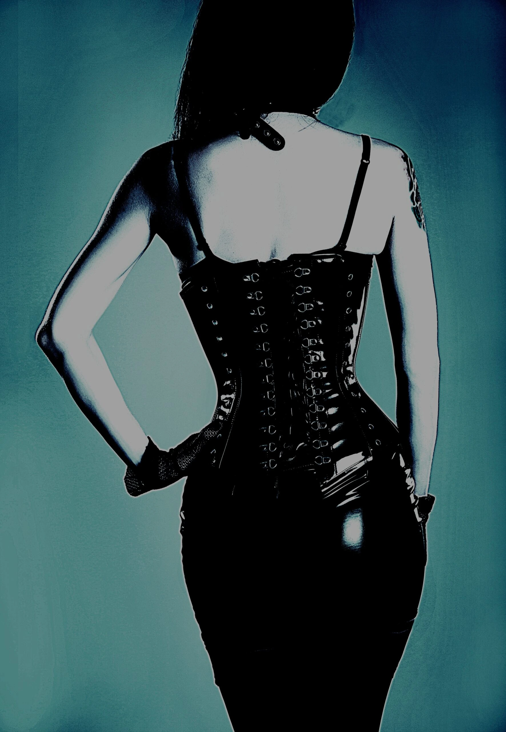 Back view of a woman in a black corset, showcasing the intricate lacing and figure-hugging fit, with hands on hips.