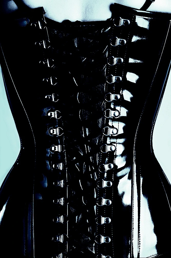 Gothic woman with dark hair and red lipstick wearing a black corset and gloves, looking to the side with a confident expression.