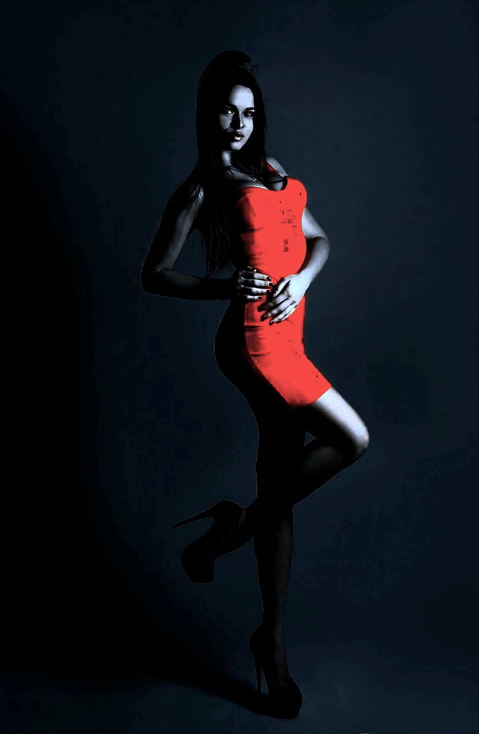 A woman in a tight red dress and high heels, striking a pose in a dark, minimalist setting.