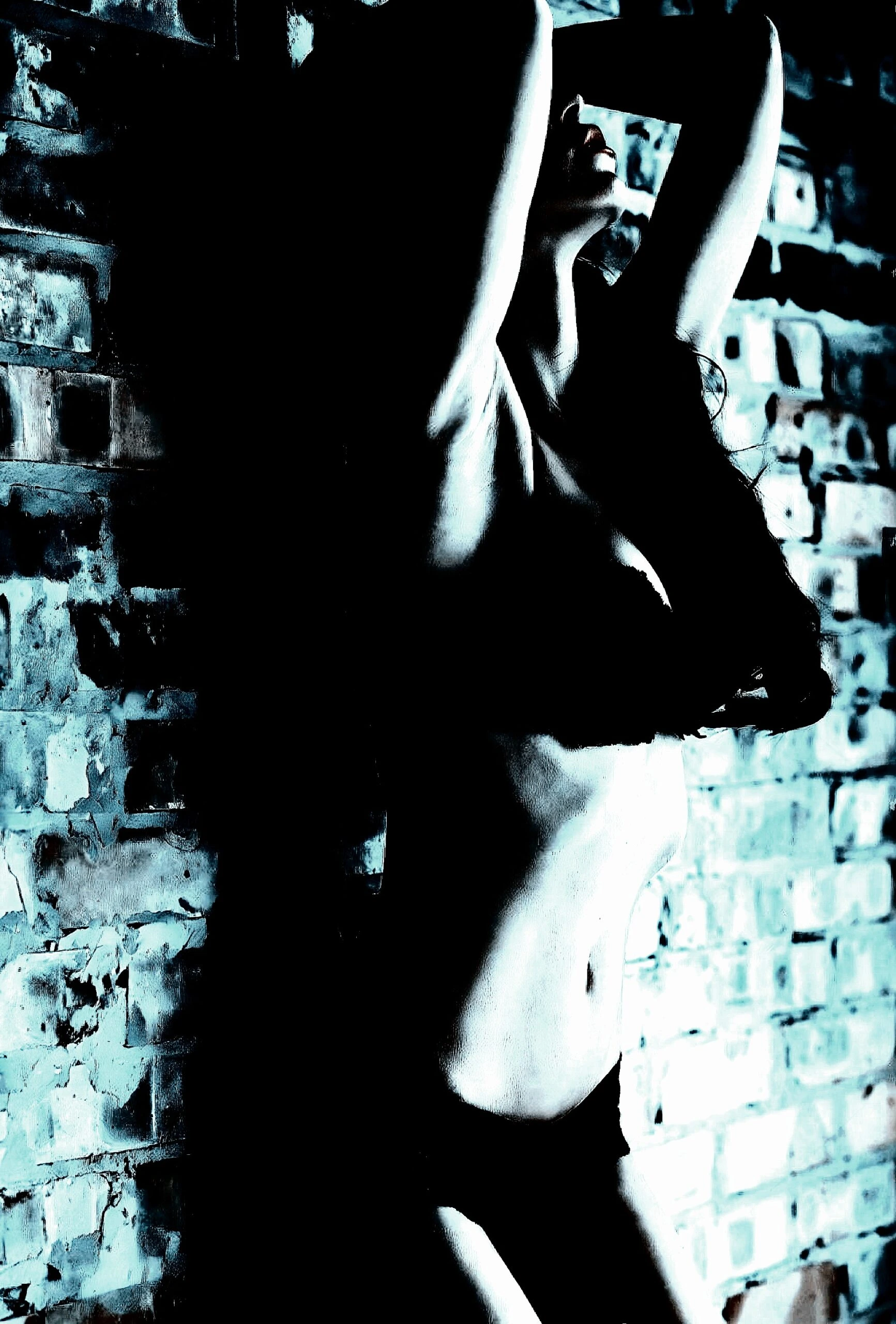 A woman in black lingerie leaning against a brick wall, with dramatic lighting creating a striking visual effect.