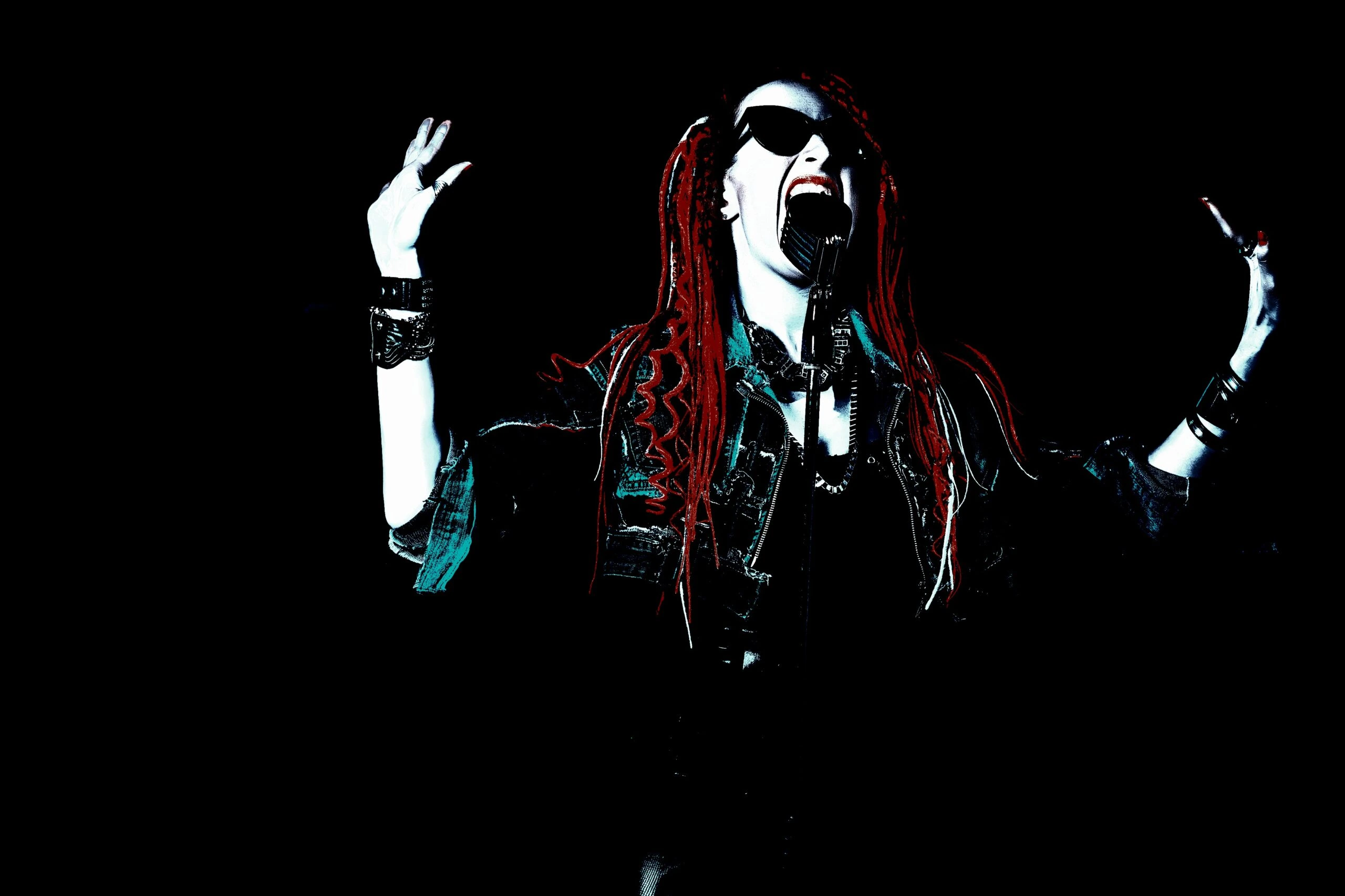 A female metal singer in mid-performance, wearing dark sunglasses and with fiery red dreadlocks, passionately belting out a song into a vintage microphone, radiating pure metal energy on stage.