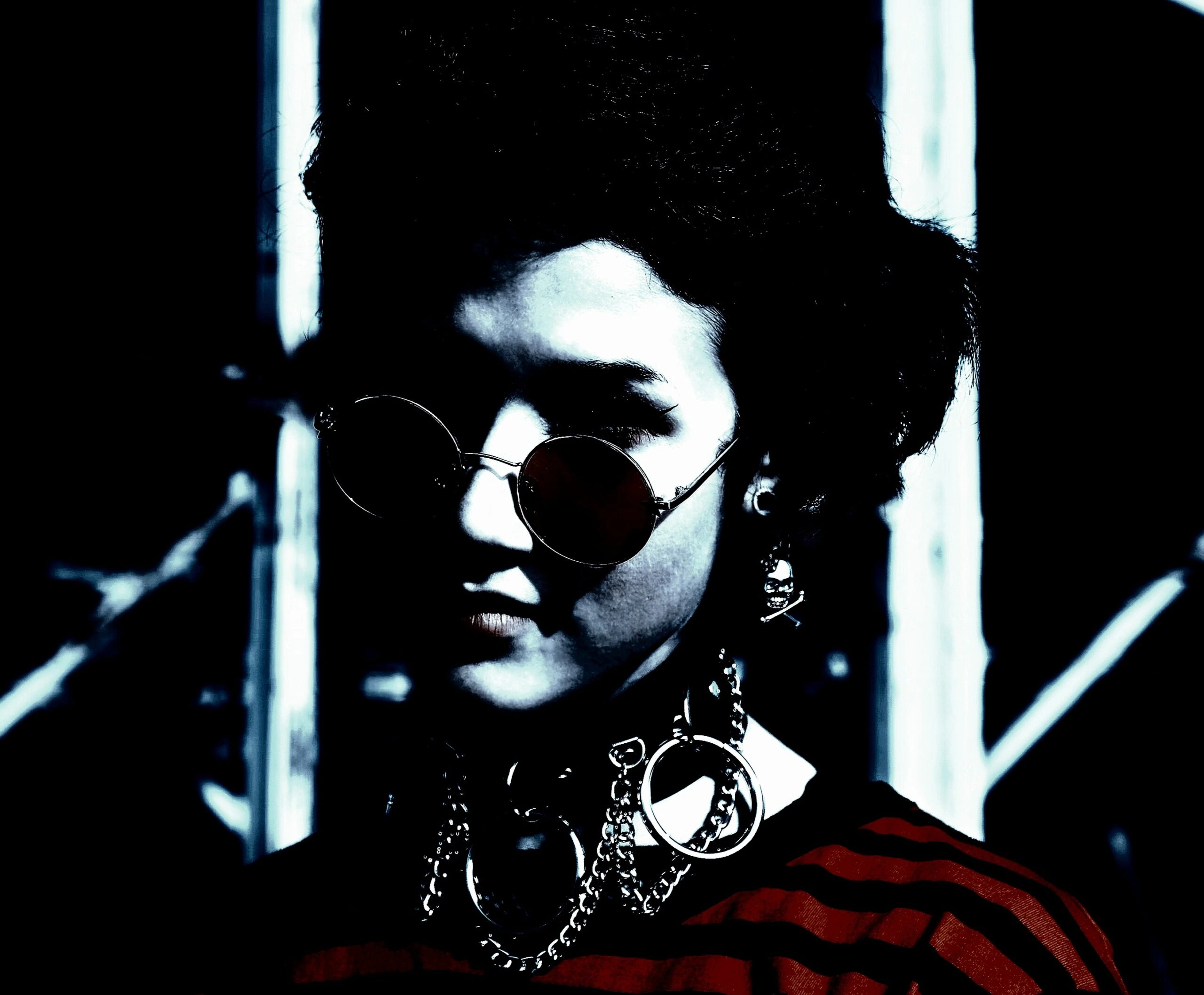 Woman with curly hair wearing black sunglasses, looking to the side with a strong, confident look.