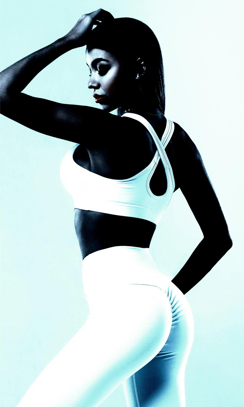 Side profile of a woman in a sleek white workout outfit, highlighting curves and confidence.