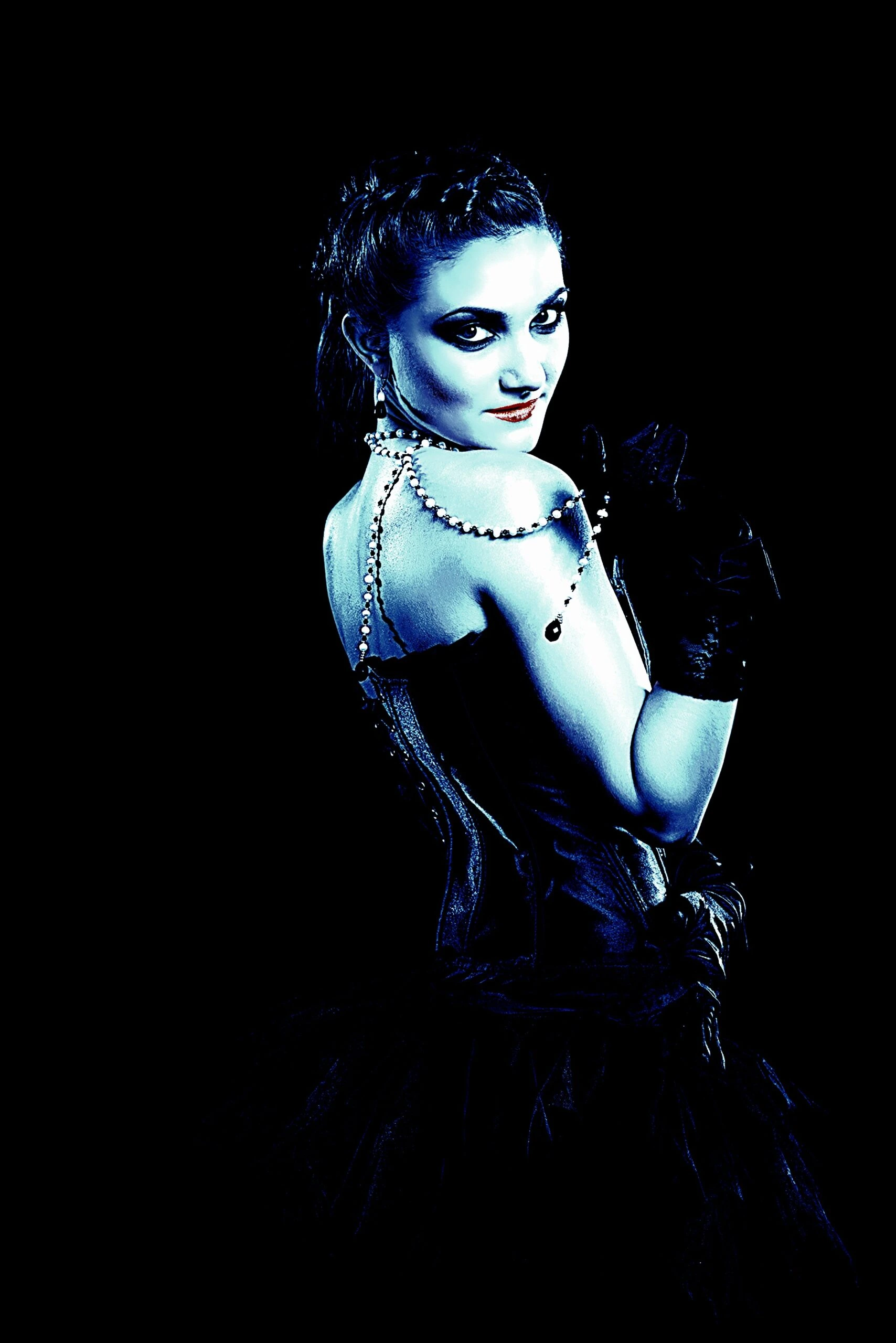 Woman in gothic attire, with dark makeup and intricate accessories, turning back towards the camera with a seductive, mysterious expression. 