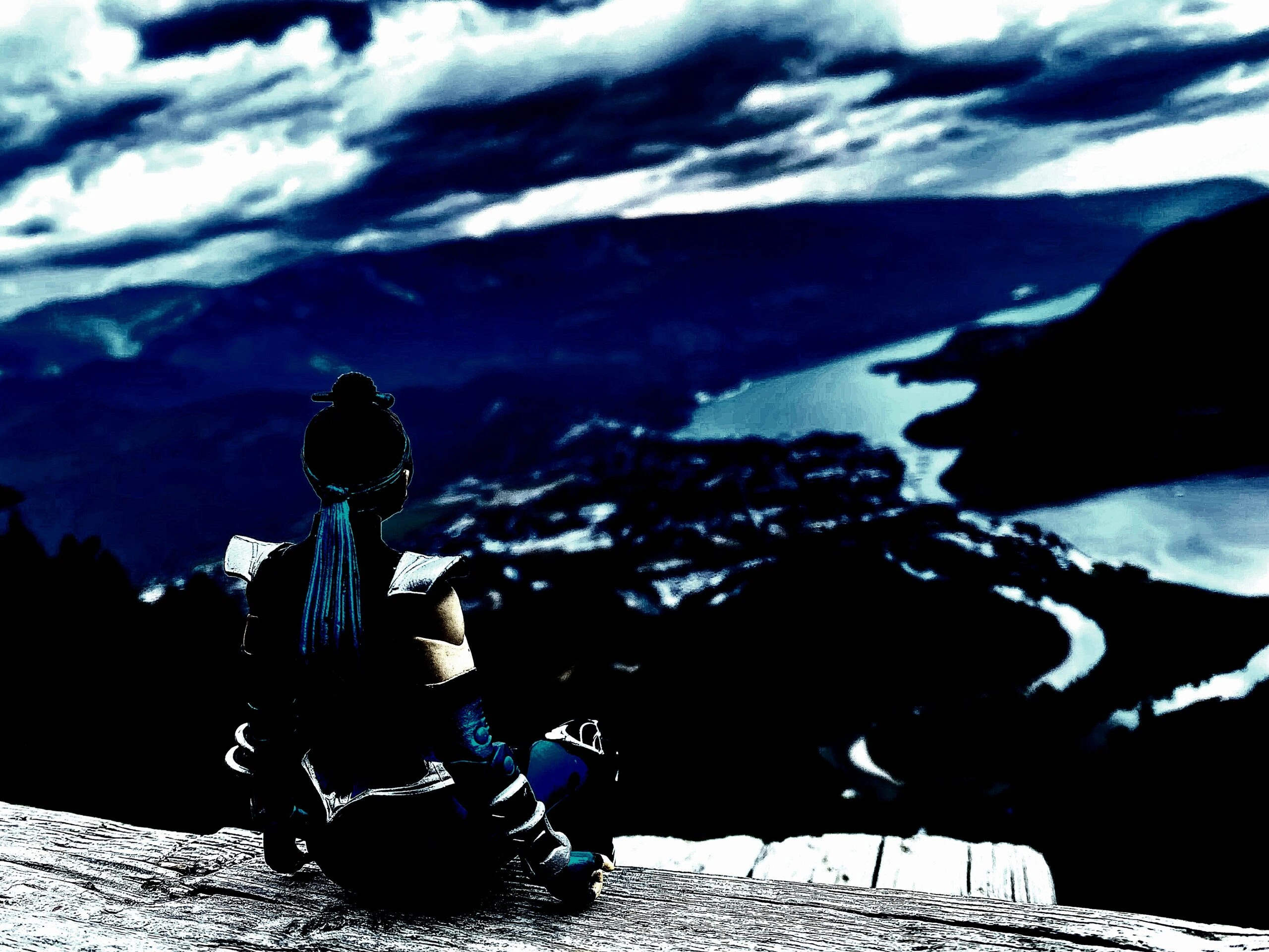 Cosplayer dressed as a fantasy warrior sitting on a wooden ledge overlooking a dramatic, stormy landscape.