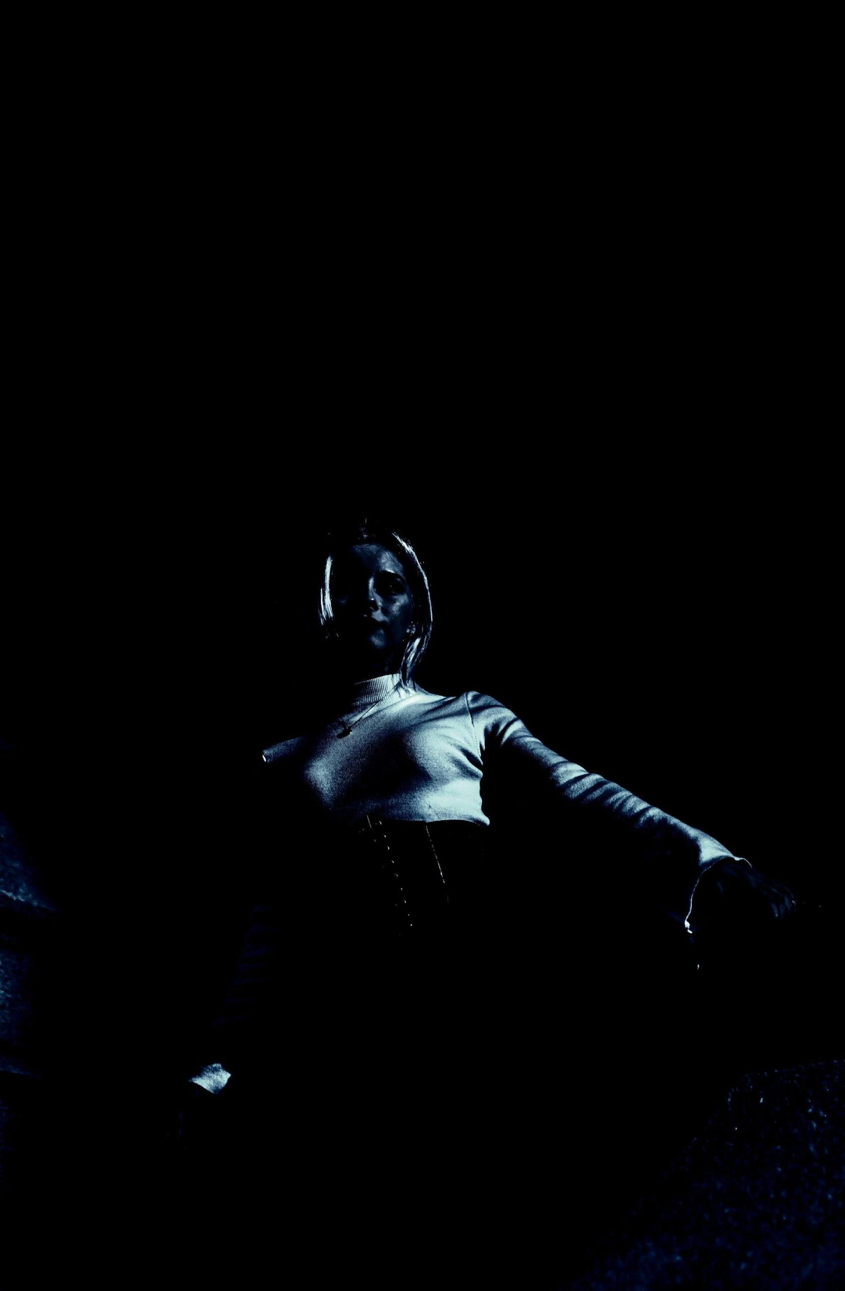 Back view of a woman in a corset with minimalist lighting, creating a mysterious silhouette.