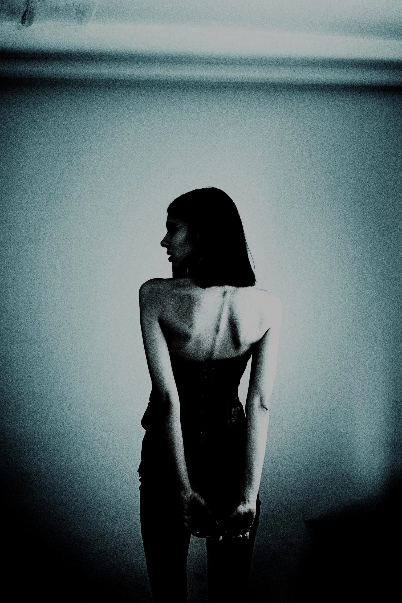 Silhouette of a woman wearing vintage lingerie with delicate lace details, in low light.