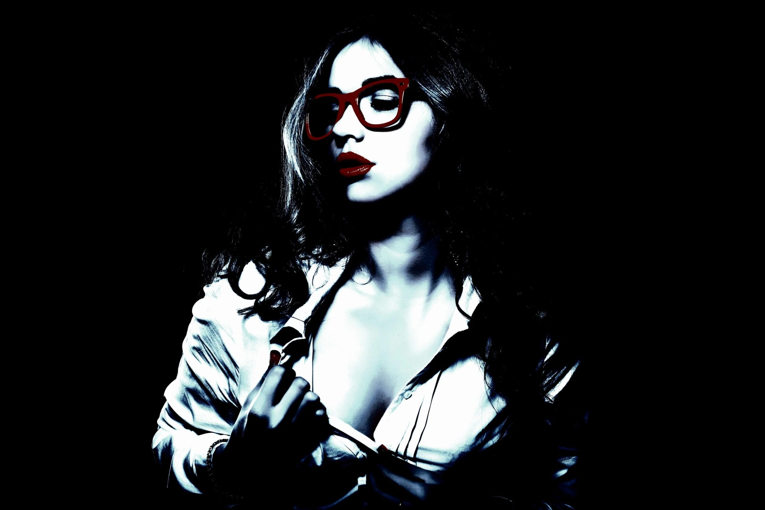 Confident woman with red glasses and a partially unbuttoned white shirt against a dark background.