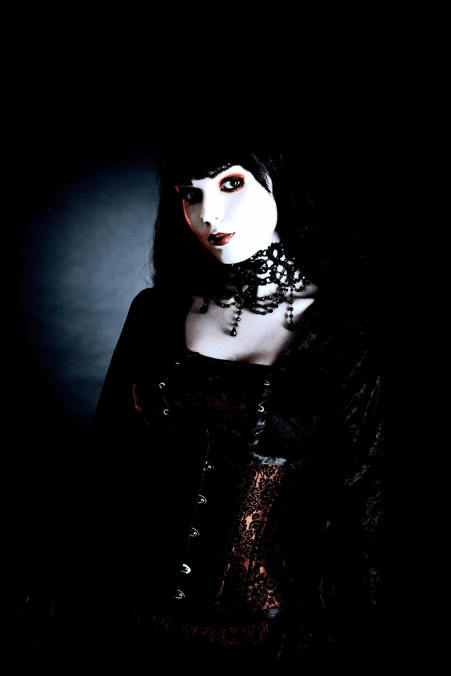 Gothic woman dressed in a black lace choker, corset, and dark clothing, exuding Victorian-inspired fashion.