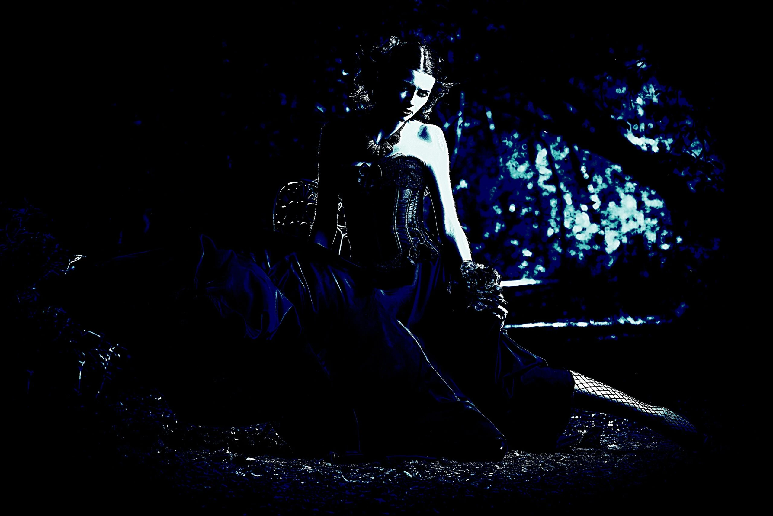 Gothic woman with a somber expression, standing in a field of tall grass, dressed in a dark, elegant gown.