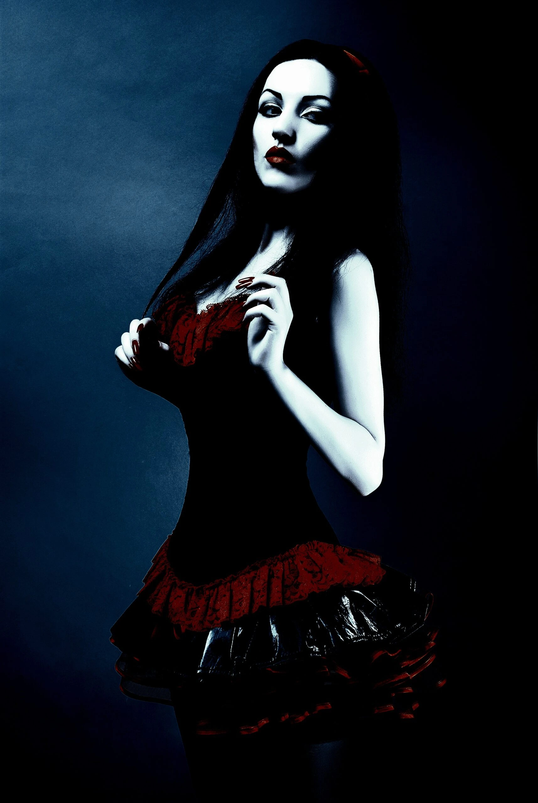 A person with long dark hair wearing a black and red corset dress with a ruffled skirt. The person's face is blurred.