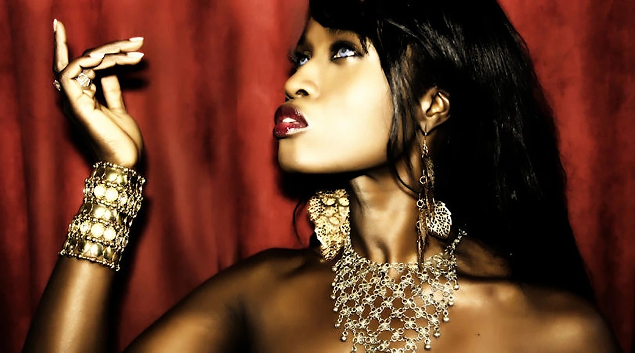 Elegant woman adorned in intricate gold jewelry, with dark red lips and a pensive, upward gaze against a red velvet backdrop.