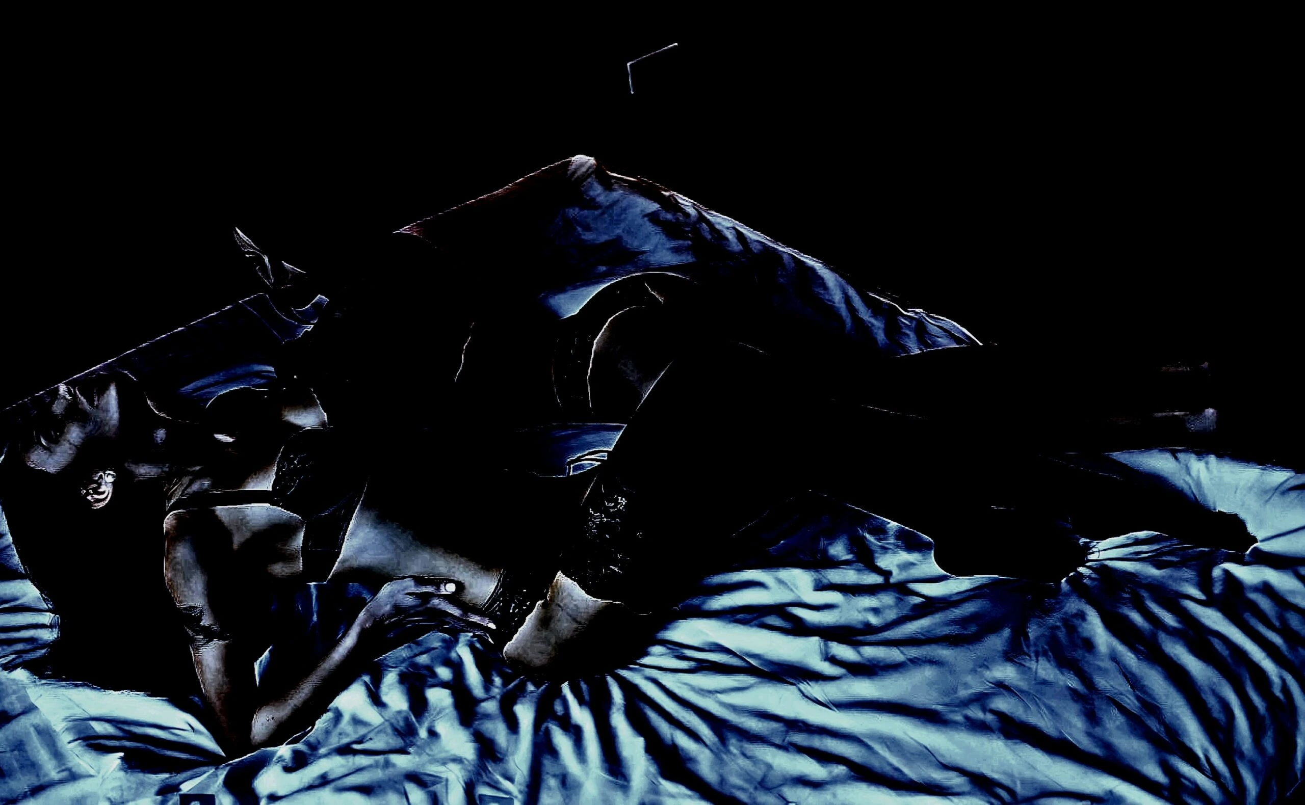 A woman lying on a bed in lingerie, with soft shadows enhancing the mysterious mood of the dimly lit scene.