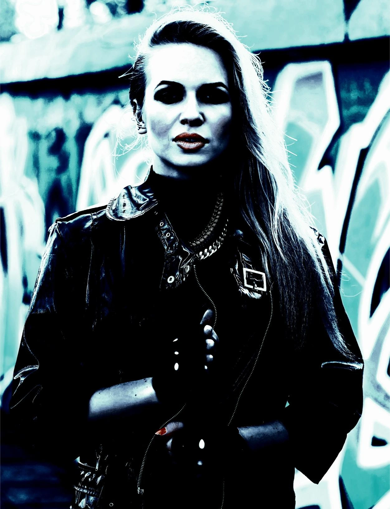 Woman in leather jacket standing confidently against a graffiti-covered wall, expressing alternative fashion.
