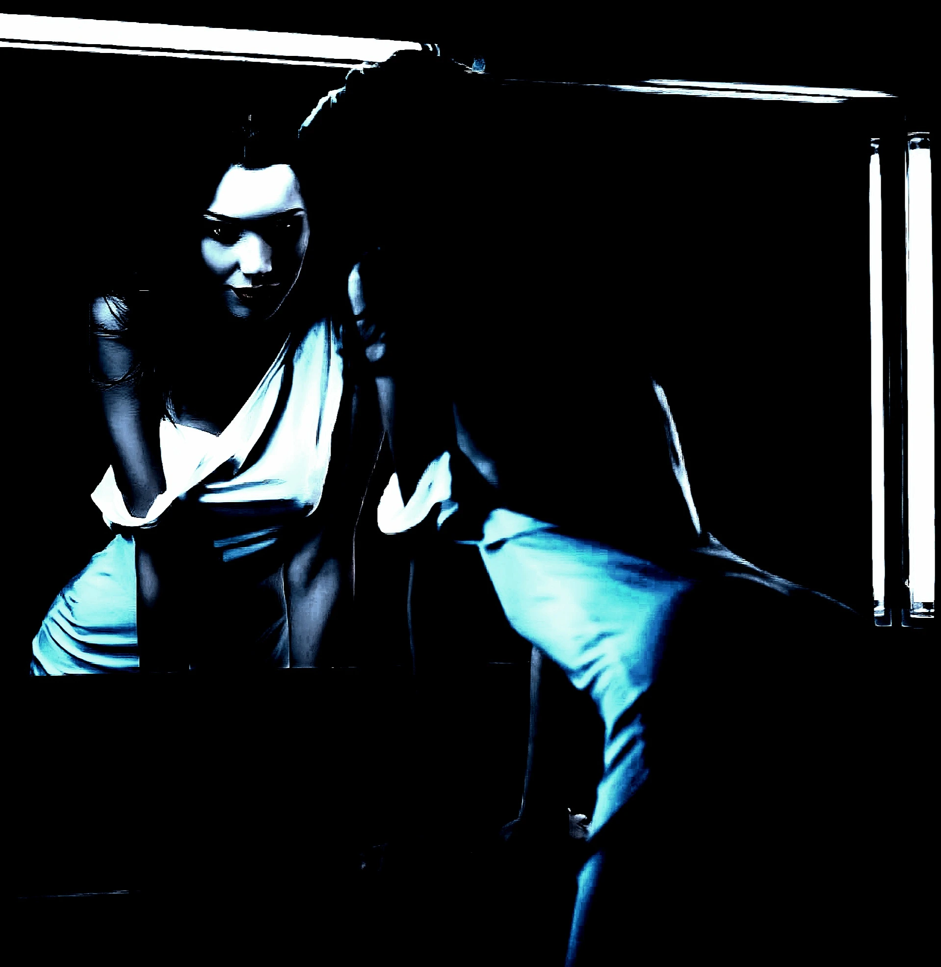 Dark-haired woman in a white dress leaning over a mirror, giving off an eerie and seductive gothic vibe.