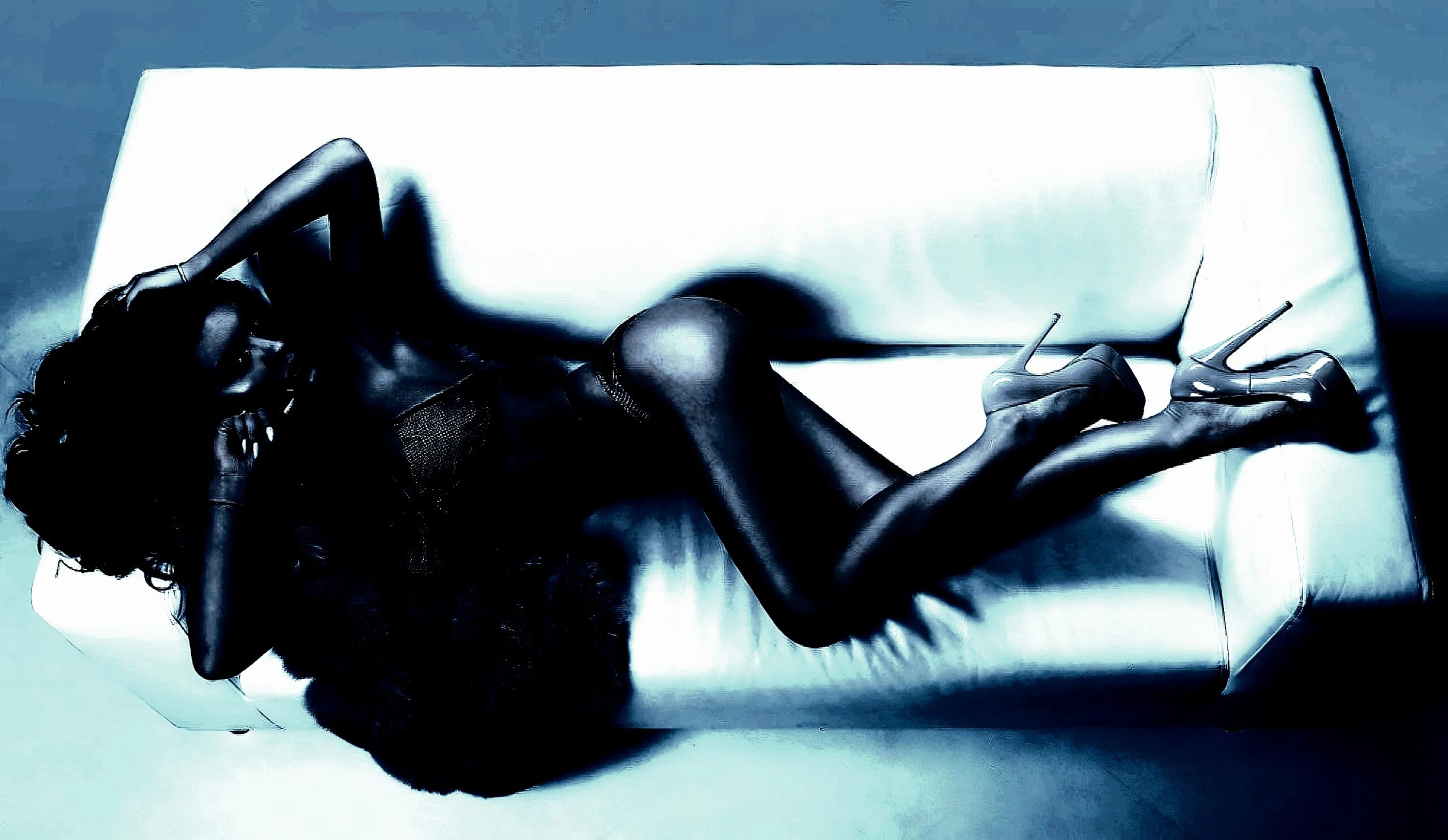 Woman reclining on a white sofa in high heels, showcasing glamour and sophistication with a sultry expression.