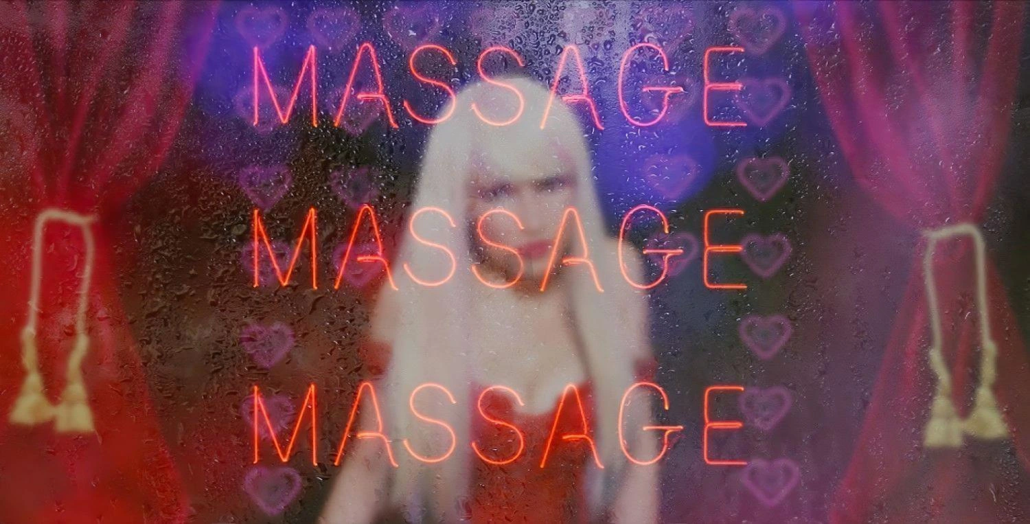 A neon sign reading "MASSAGE" in red glows behind a rain-covered window, with a blurred blonde woman in the background wearing red.