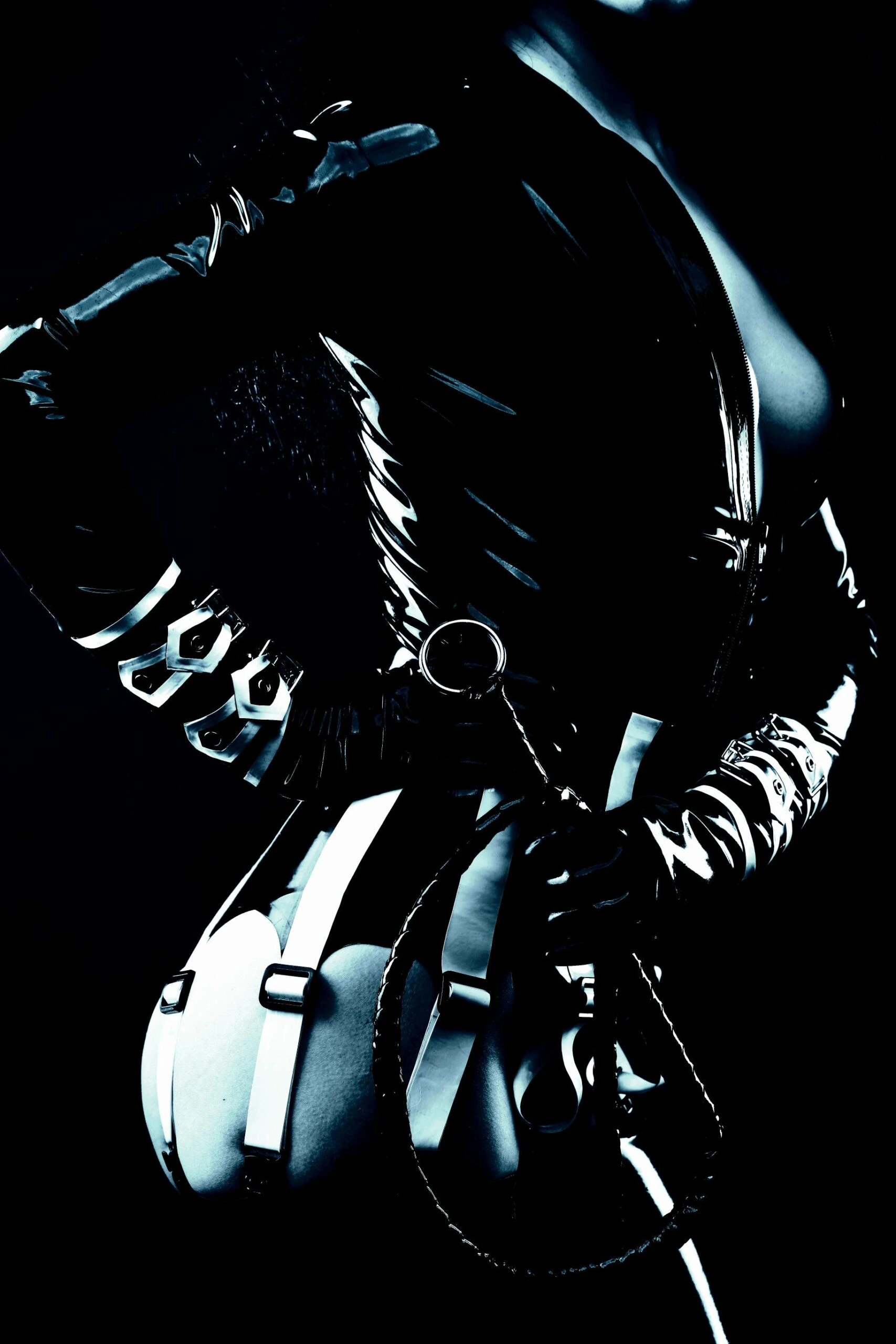Close-up of a woman in a latex outfit with metallic accents, exuding a strong, commanding presence.