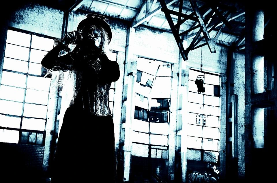Steampunk-inspired woman in a corset, standing in an abandoned industrial building with dramatic lighting.