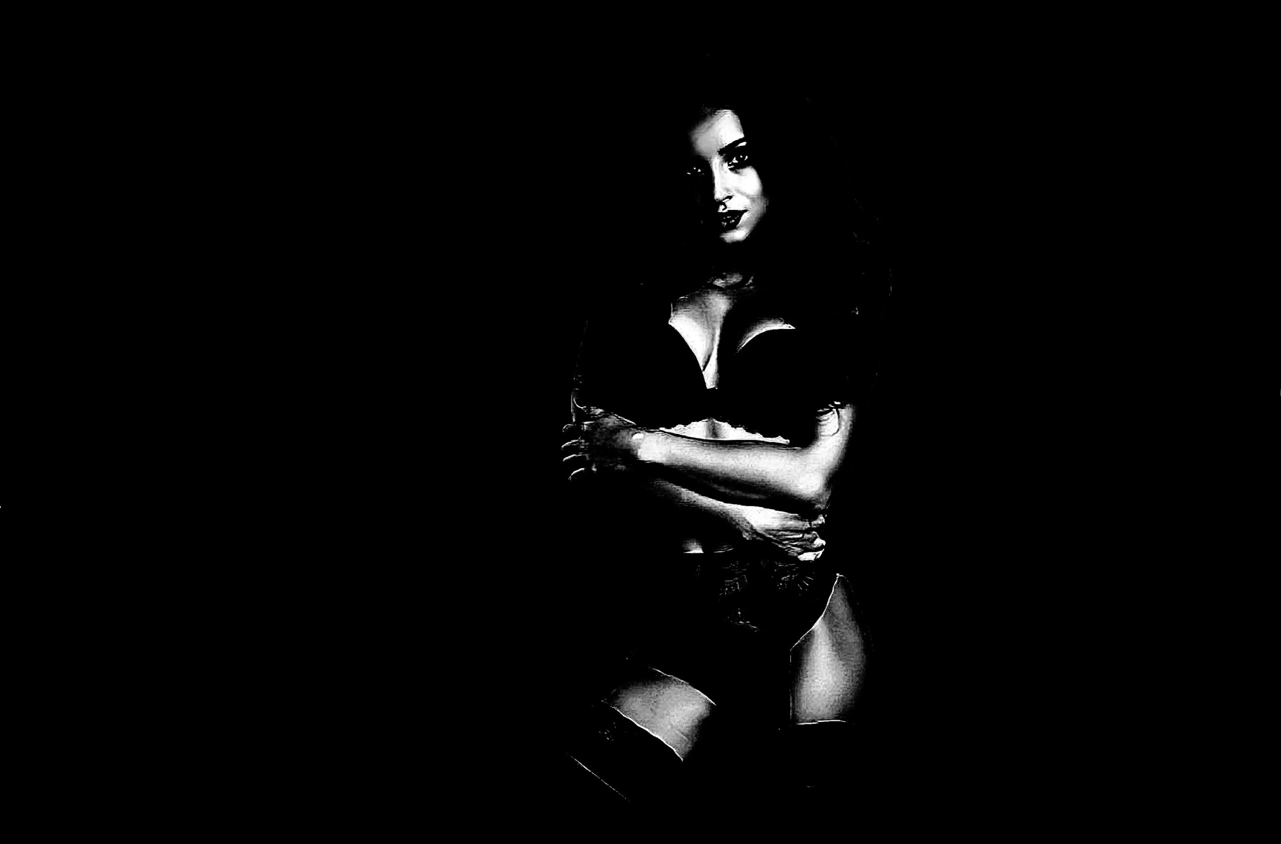 Black and white artistic photo of a woman in lingerie, seated with arms crossed in an intimate pose.