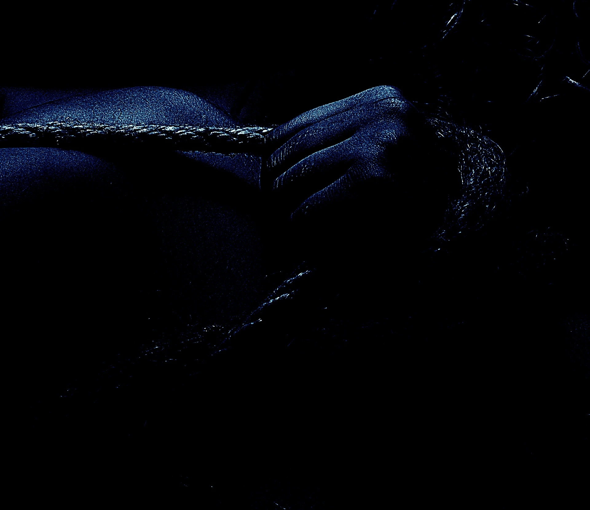 A close-up of a hand gripping a thick rope, illuminated by moody lighting.
