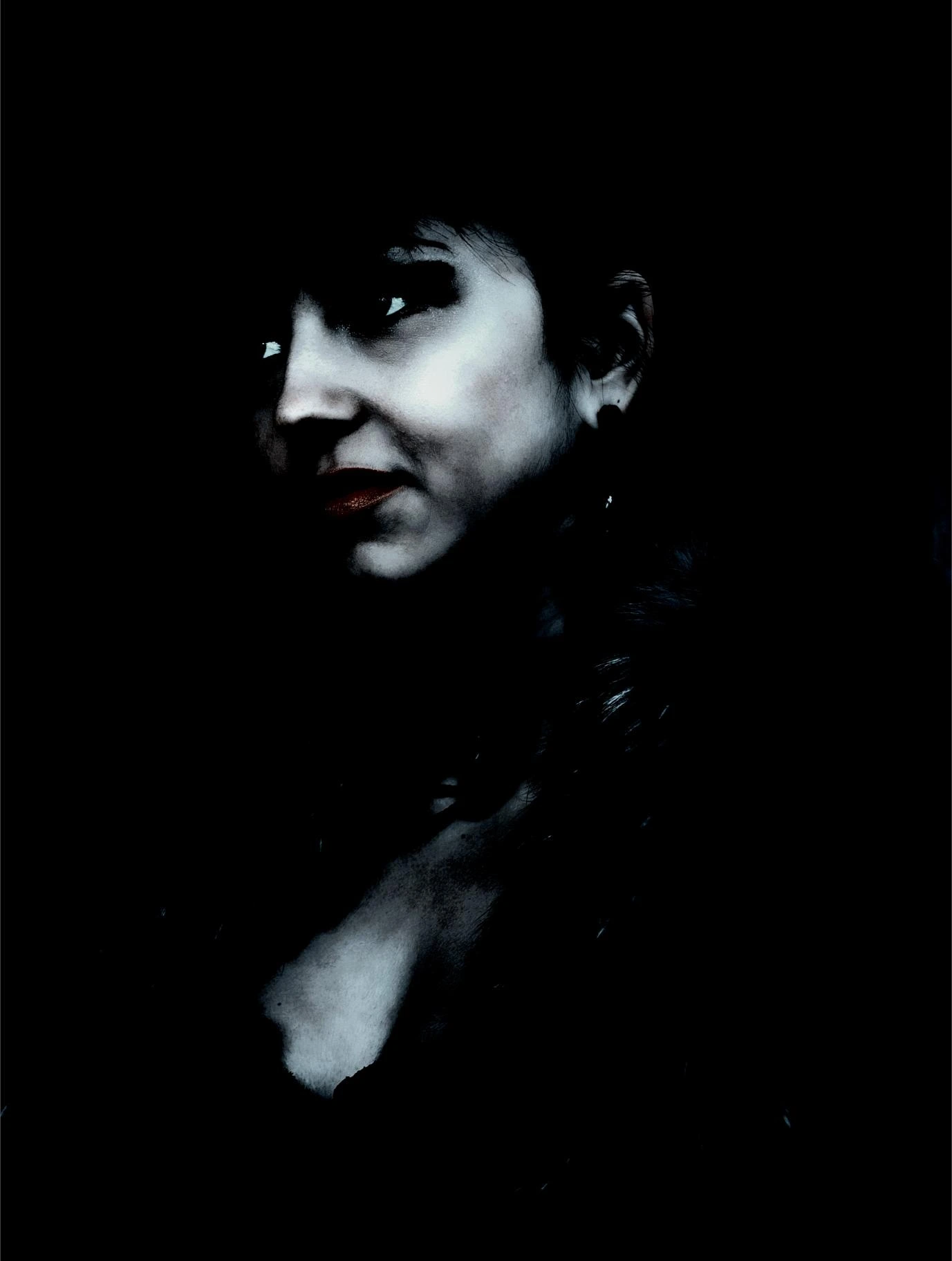Close-up of a woman’s face in shadow, with bold makeup and dark lipstick, embodying dark romantic goth elegance.