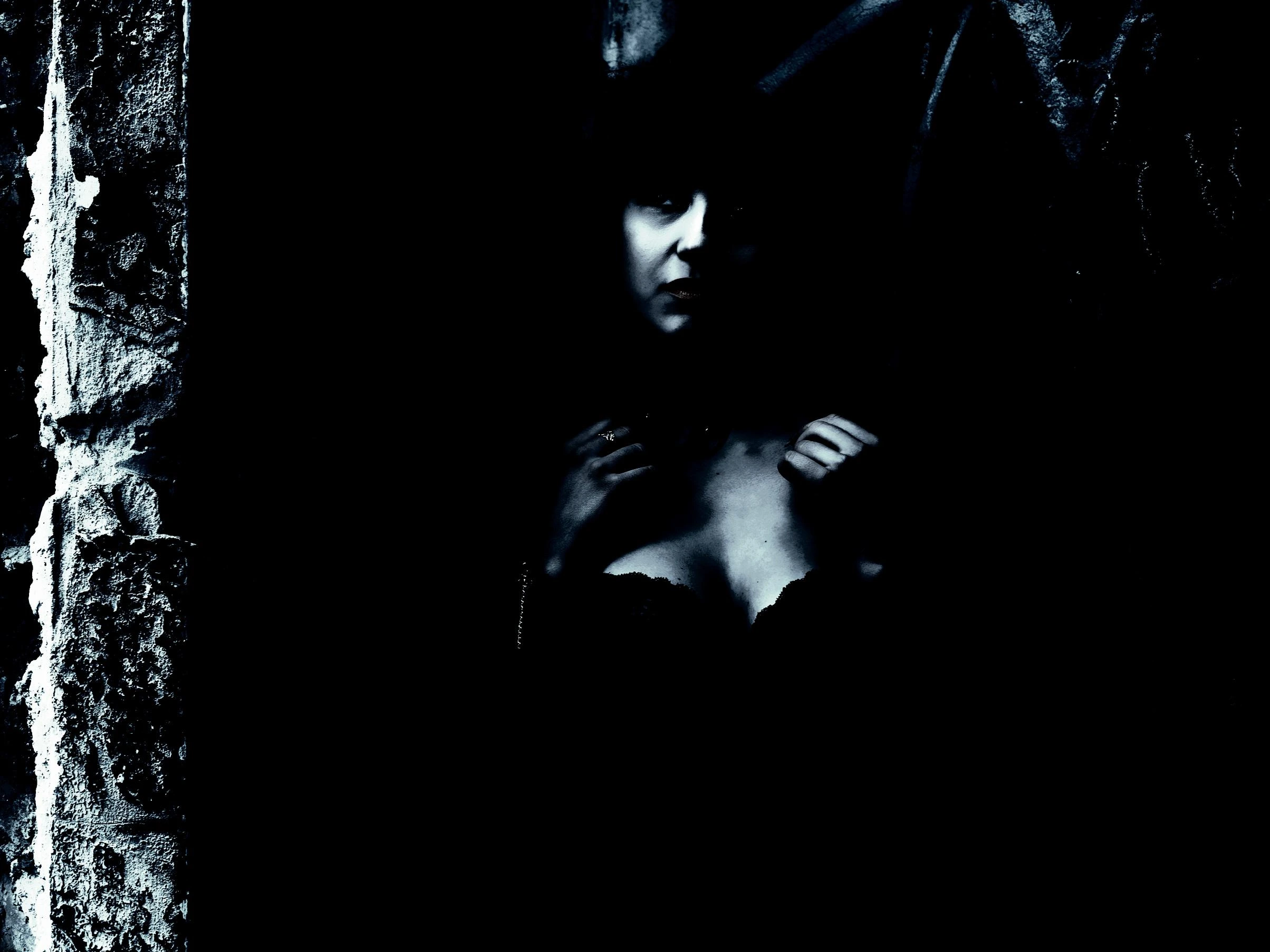 Woman in a black lace corset standing in a dark stone archway, radiating gothic mystery and sensuality.