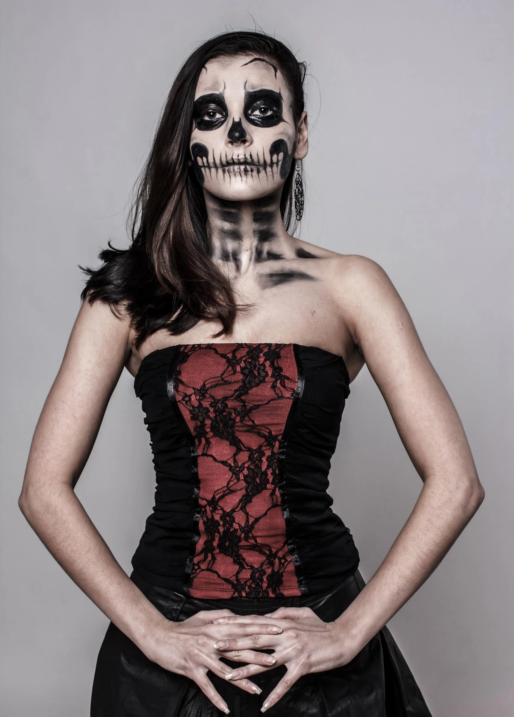 Woman in a gothic red and black lace corset, wearing skull-inspired makeup.
