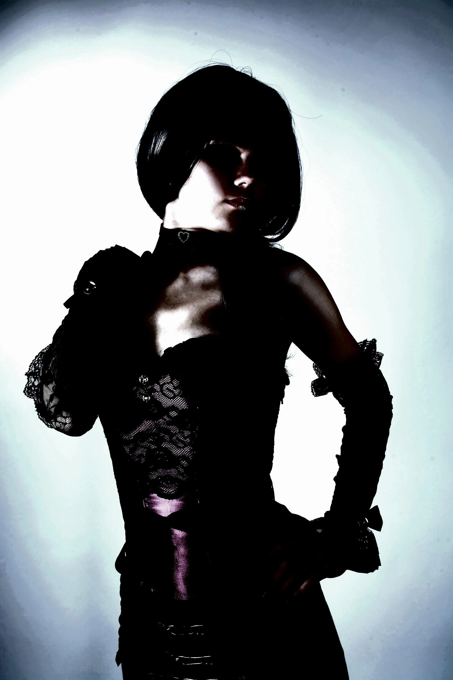 Shadowed figure in a black lace corset with purple accents, posing with dark elegance.