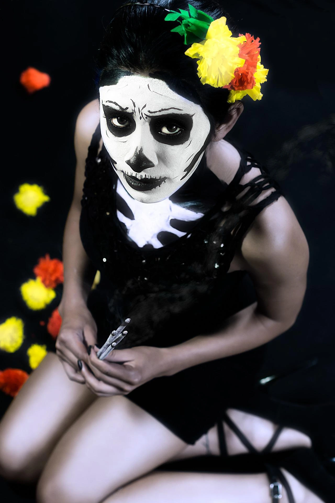 Woman in black dress with Day of the Dead skull makeup and colorful flowers in her hair