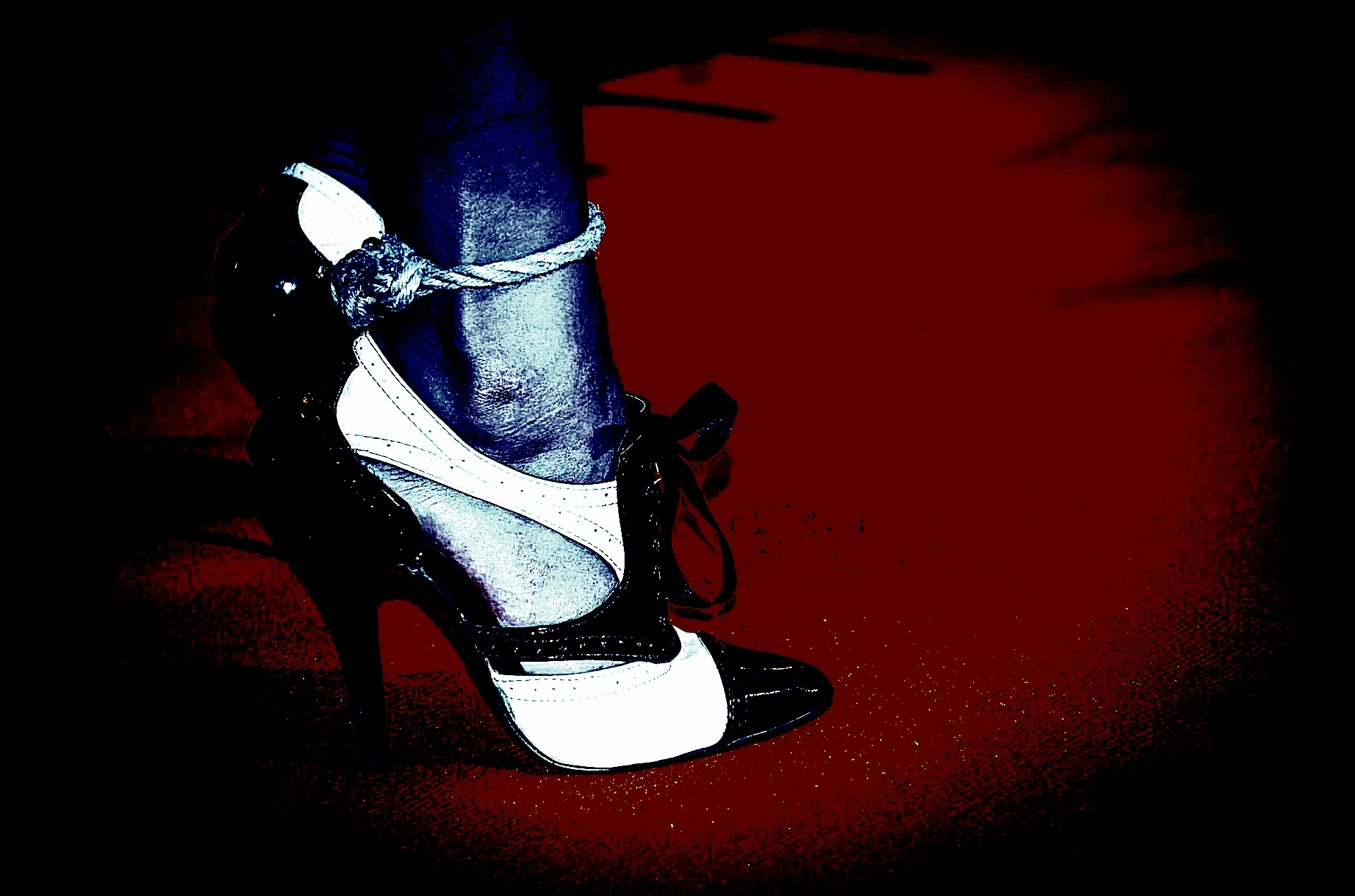 Foot in high heels tied with rope on red floor, symbolizing restraint and contrast