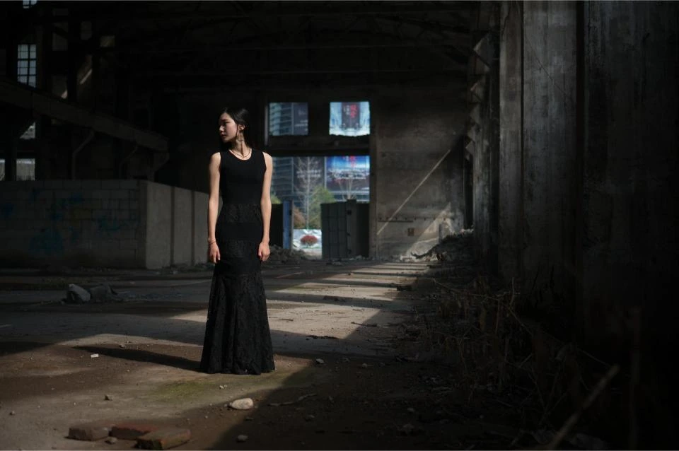 Full view of woman in long black lace gothic skirt standing in abandoned warehouse