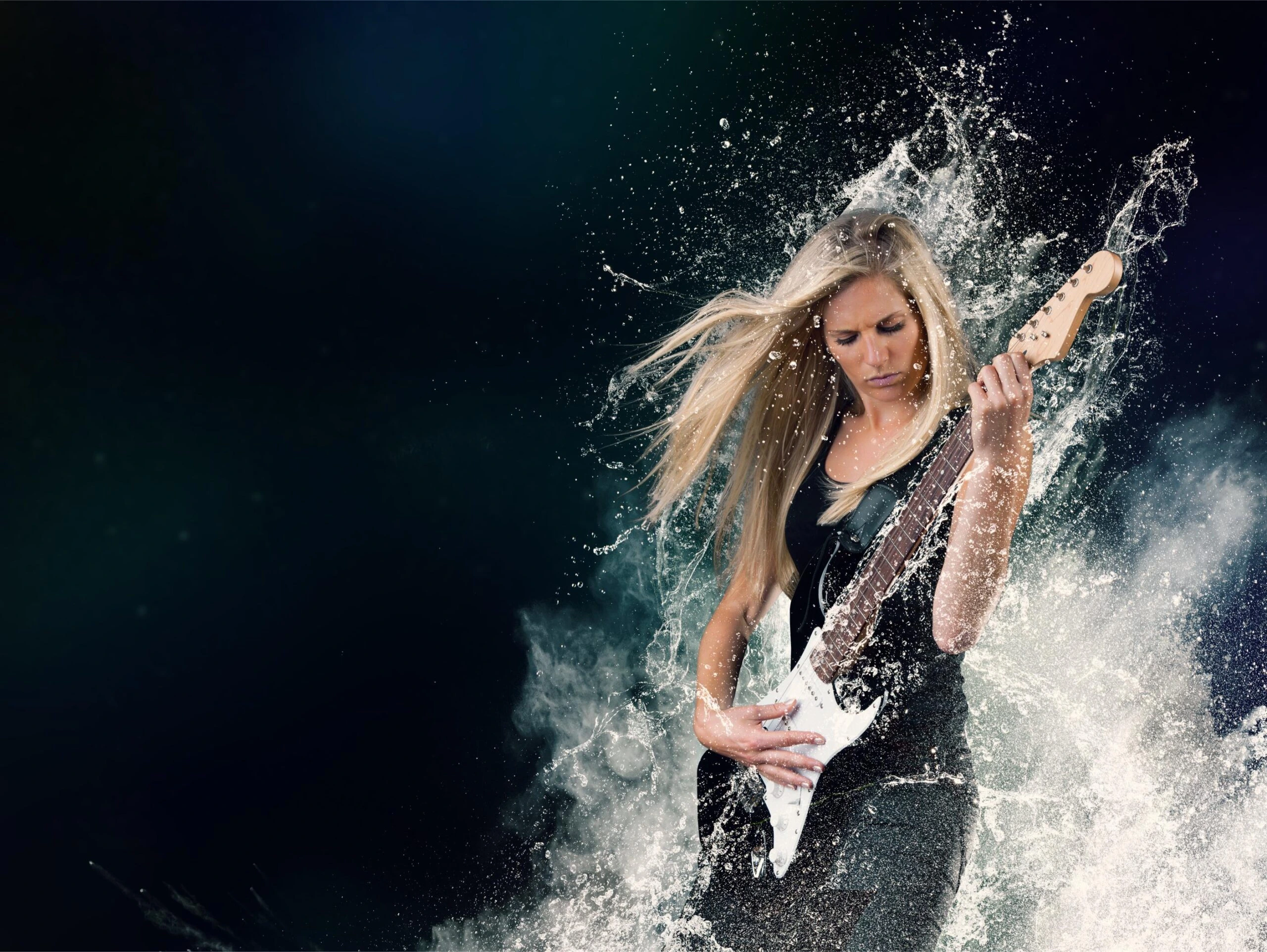 Blonde woman playing electric guitar as water splashes dramatically around her.