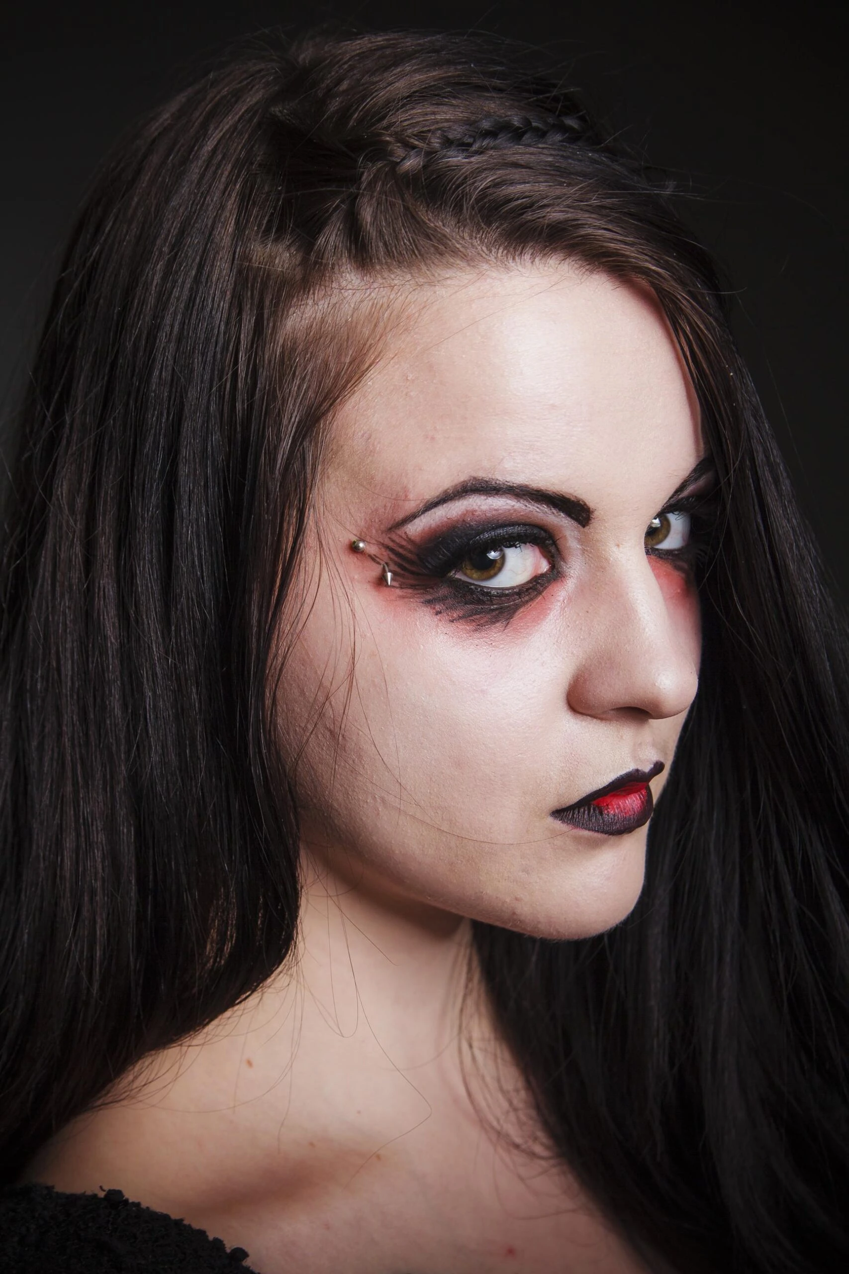 Close-up of gothic woman with heavy black and red makeup and piercing stare