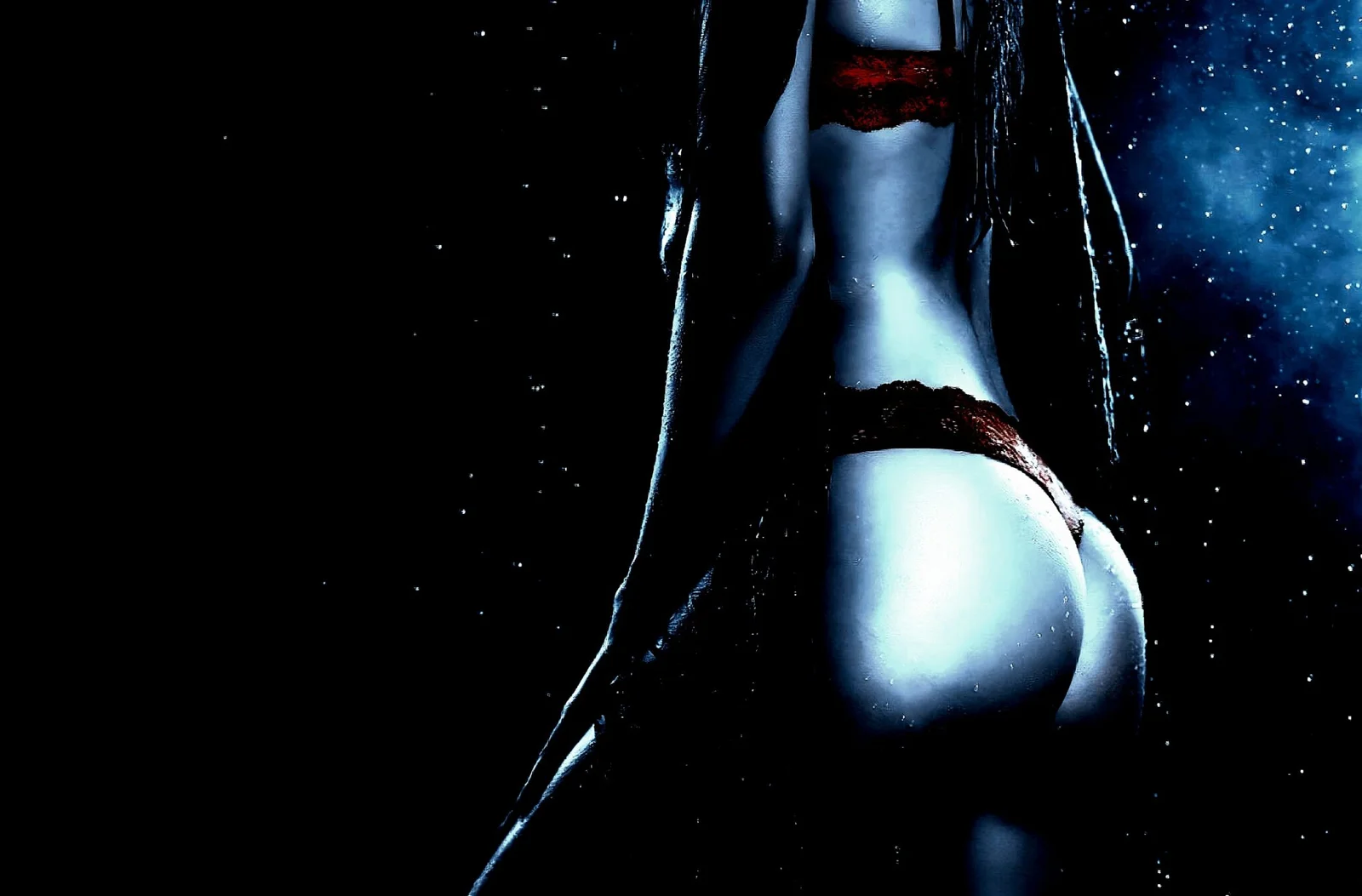 Woman in red lingerie standing in the dark, dramatic lighting emphasizing curves and gothic aesthetic.