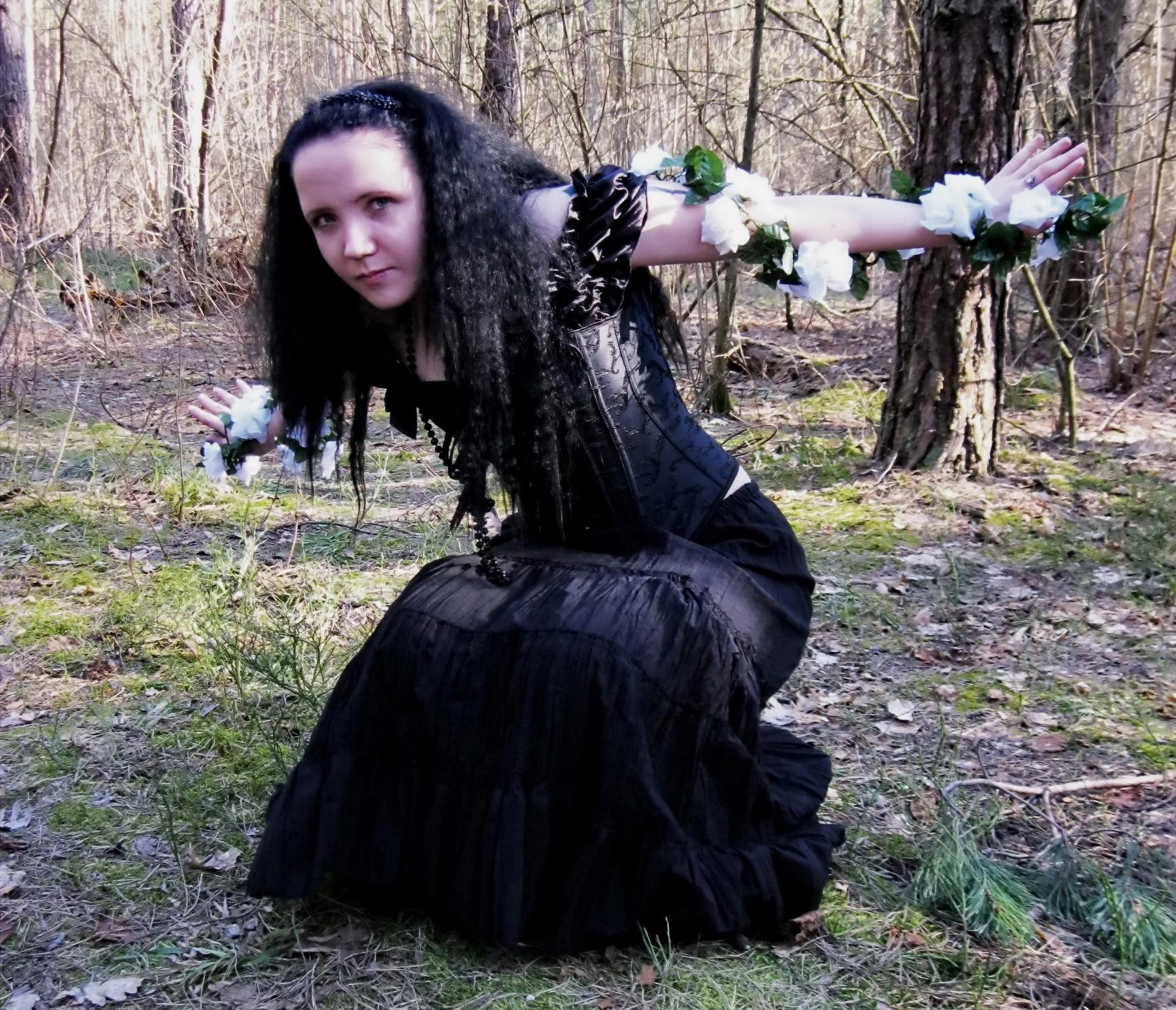 Goth woman with dark hair in a black off-the-shoulder dress, holding a glowing lantern.
