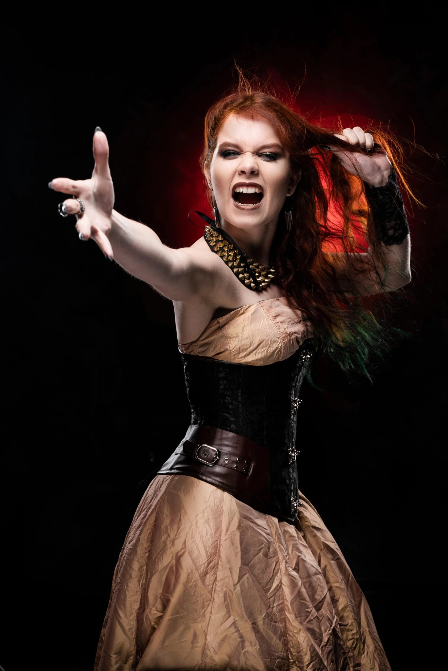 Red-haired woman in a black gothic corset screaming and reaching toward the camera.